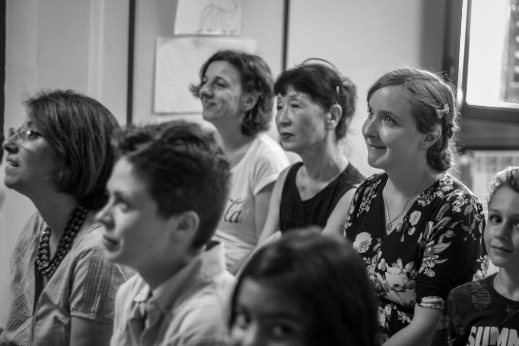 Ikuko sits in a crowd of students looking pensive.