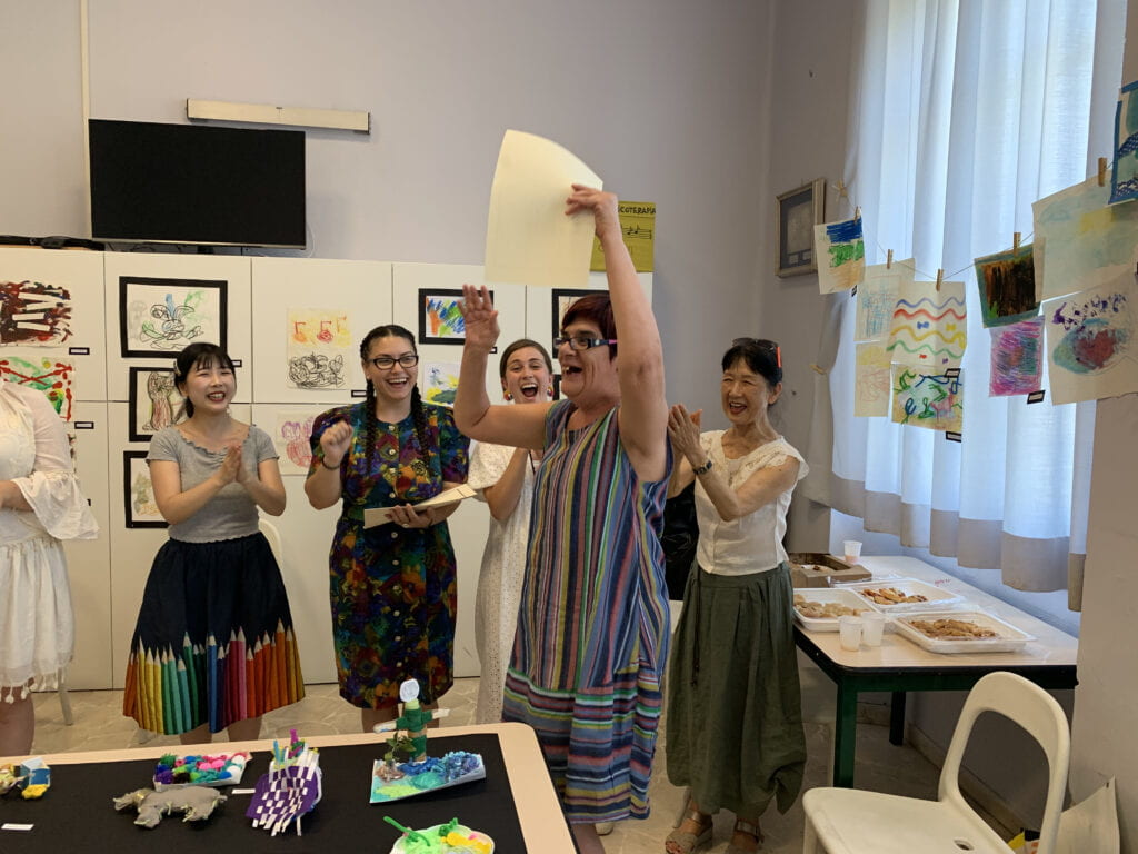 A group of students stand around one presenting student and celebrate their work.