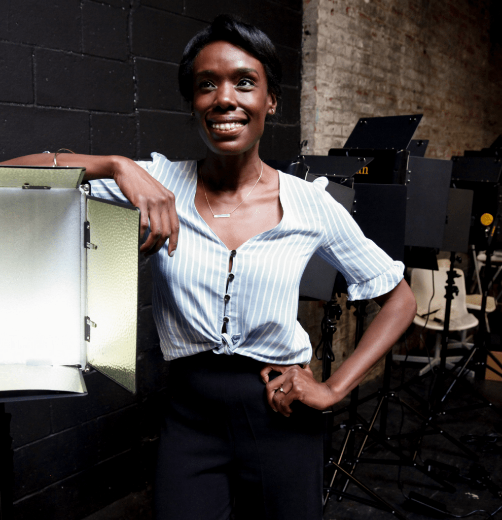 alum Kweighbaye Kotee standing on a film set with her hands on her hips