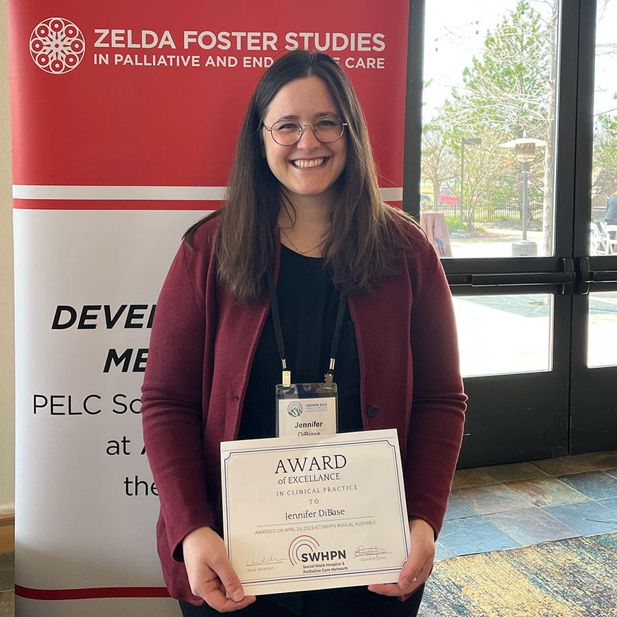 Jennifer DiBiase stands in front of a Zelda Foster banner holding her award