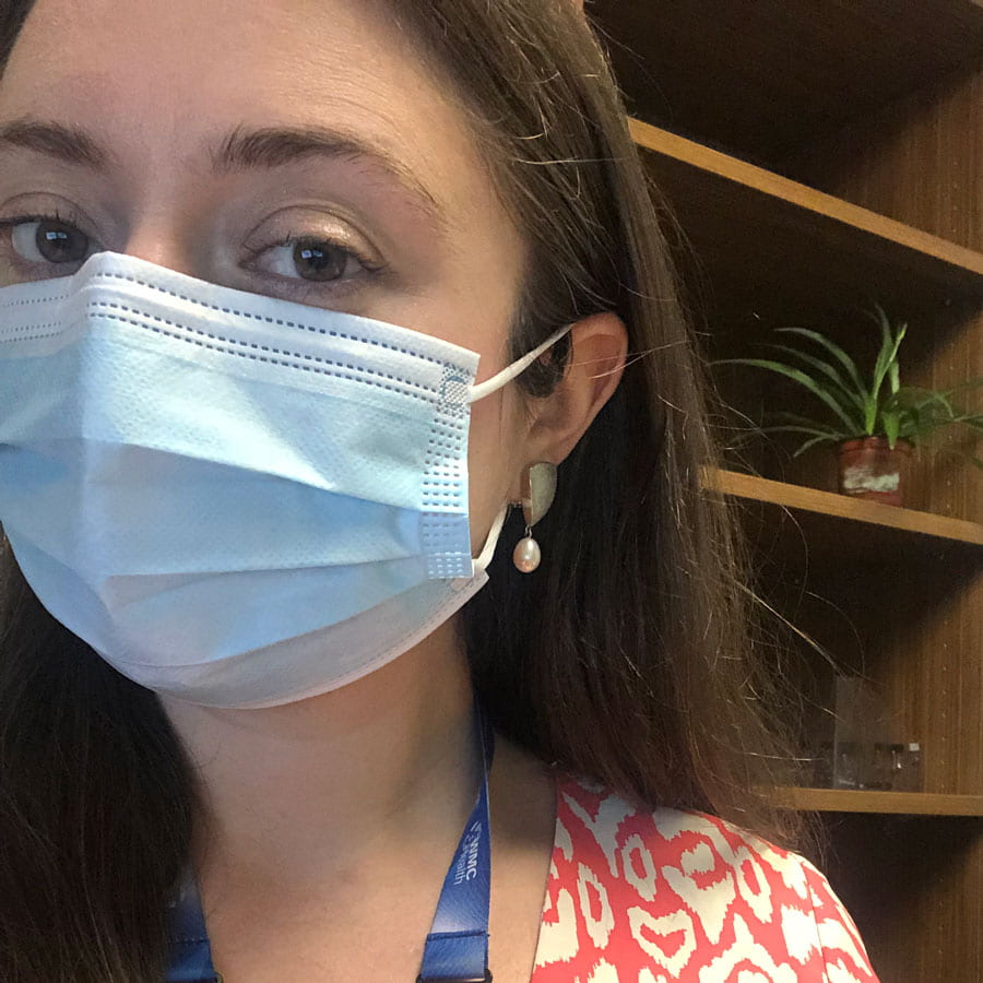 Kaila Robertson in front of a bookcase wearing a surgical mask