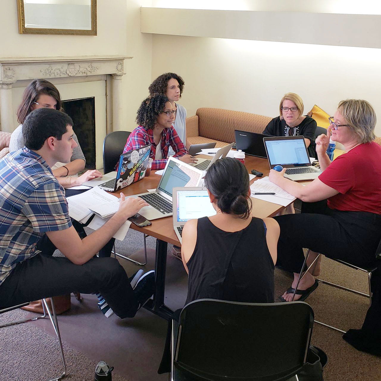 Michelle Munson and members of the Youth and Young Adult Mental Health Group seated around a table with open laptops, papers, and pens