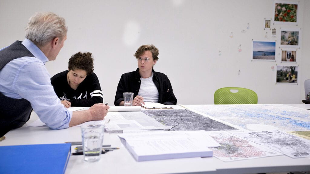 Students and a professor seated at a table covered in maps.