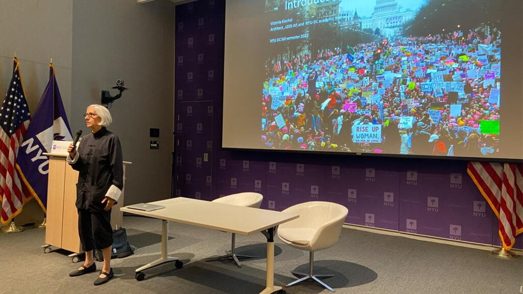 A professor lecturing in front of a projection screen.