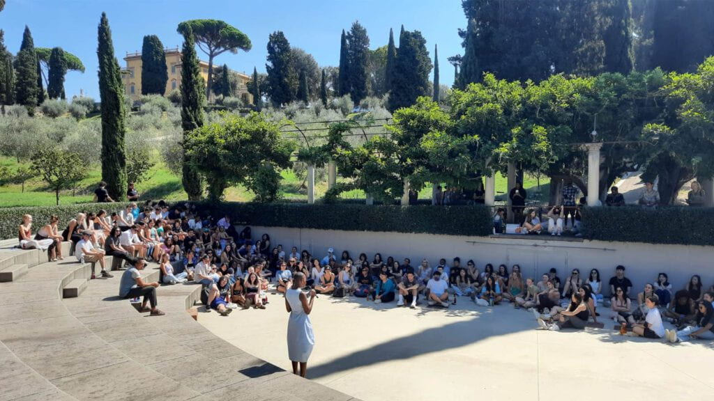 Students sitting in the amphitheater as they learn from an authority figure.