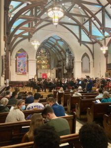 Interior of the Church of the Epiphany. Stained glass windows and people sitting in pews.