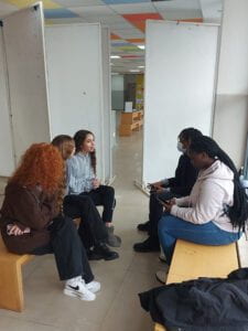 Five students sitting on benches in discussion