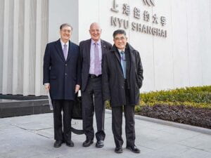 Jeffrey Lehman, Andy Hamilton, and Tong Shijun in front of a building with the NYU Shanghai logo