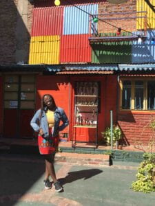 Maureen Zeufack smiles at the camera with a brightly colored building behind her