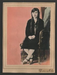 A studio portrait of a seated woman wearing a dark dress