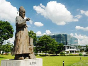 Statue of Jang Yeong-sil in front of trees and glass building