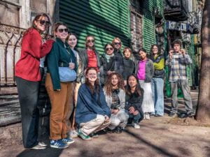 A group of students smile at the camera on a city sidewalk