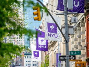 NYU flags attached to building with a West 4th Street sign in the foreground