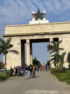 A small group of people standing in front of Black Star Gate in Accra