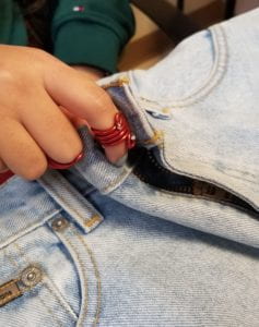 THE TIP OF THE INDEX FINGER AND THE MIDDLE FINGER ARE WEARING THE ALUMINUM WIRE ORTHOSES AND HAVE MORE STABILITY TO HOLD ONTO THE JEAN SHORT BUTTON