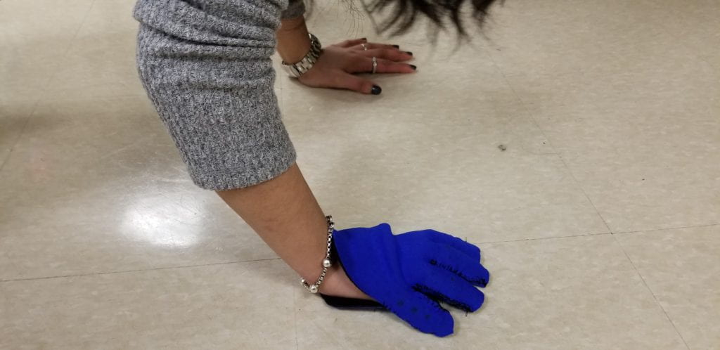 THE PATIENT IS ATTEMPTING A PLANK POSITION WITH THE GLOVE ON WITH OBSERVABLE SLIPPAGE DUE TO THE GLOVE BEING HEAVILY WEIGHTED DISTALLY