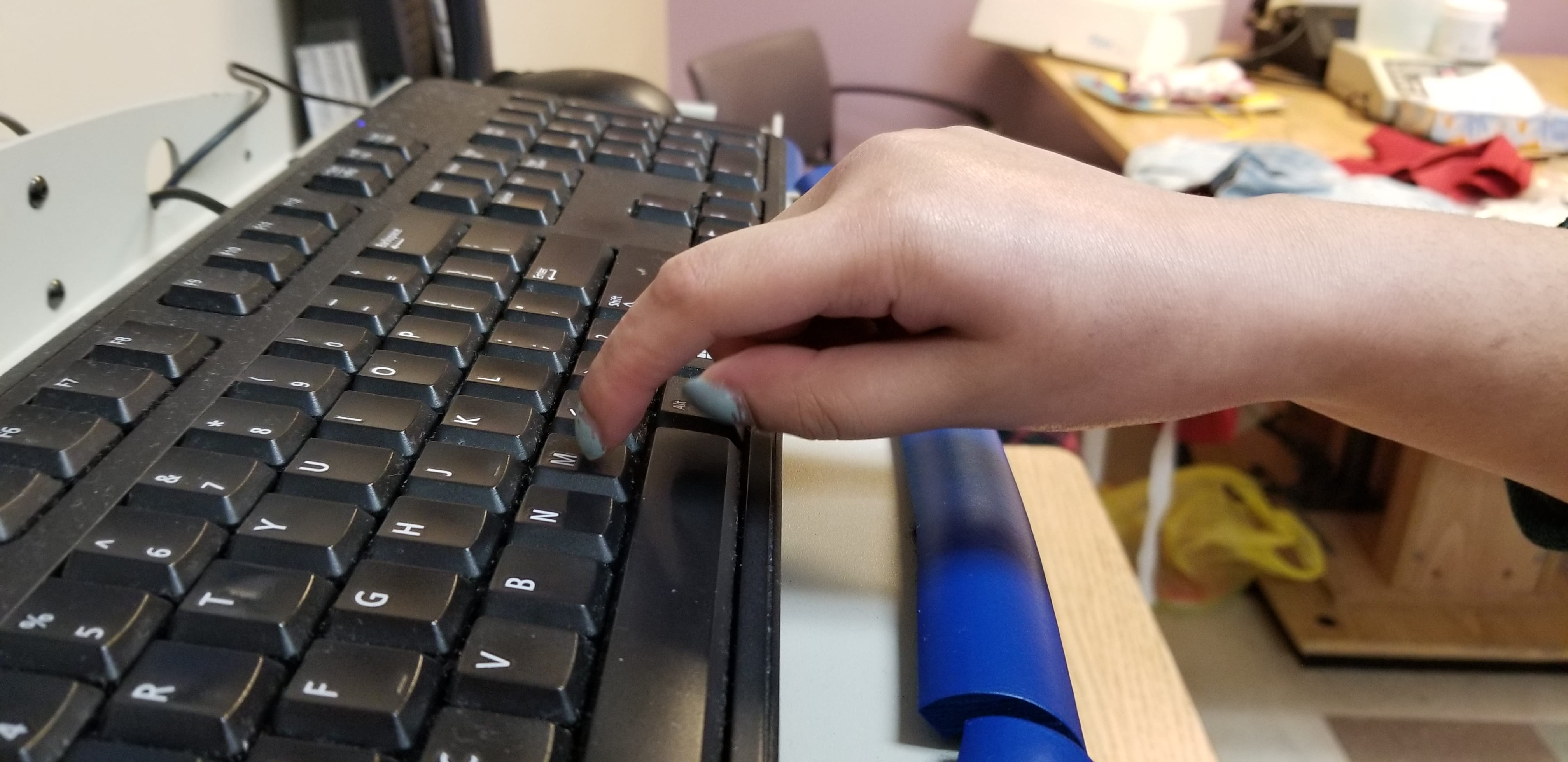 TIP OF INDEX FINGER IS ATTEMPTING TO TYPE ON A KEYBOARD BUT THE TIP OF THE FINGER IS NOT STABLE ENOUGH TO PUSH THE BUTTON