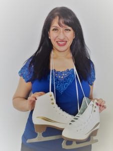 Image of female with brown skin and black hair in a blue t-shirt holding figure skates tied around the neck