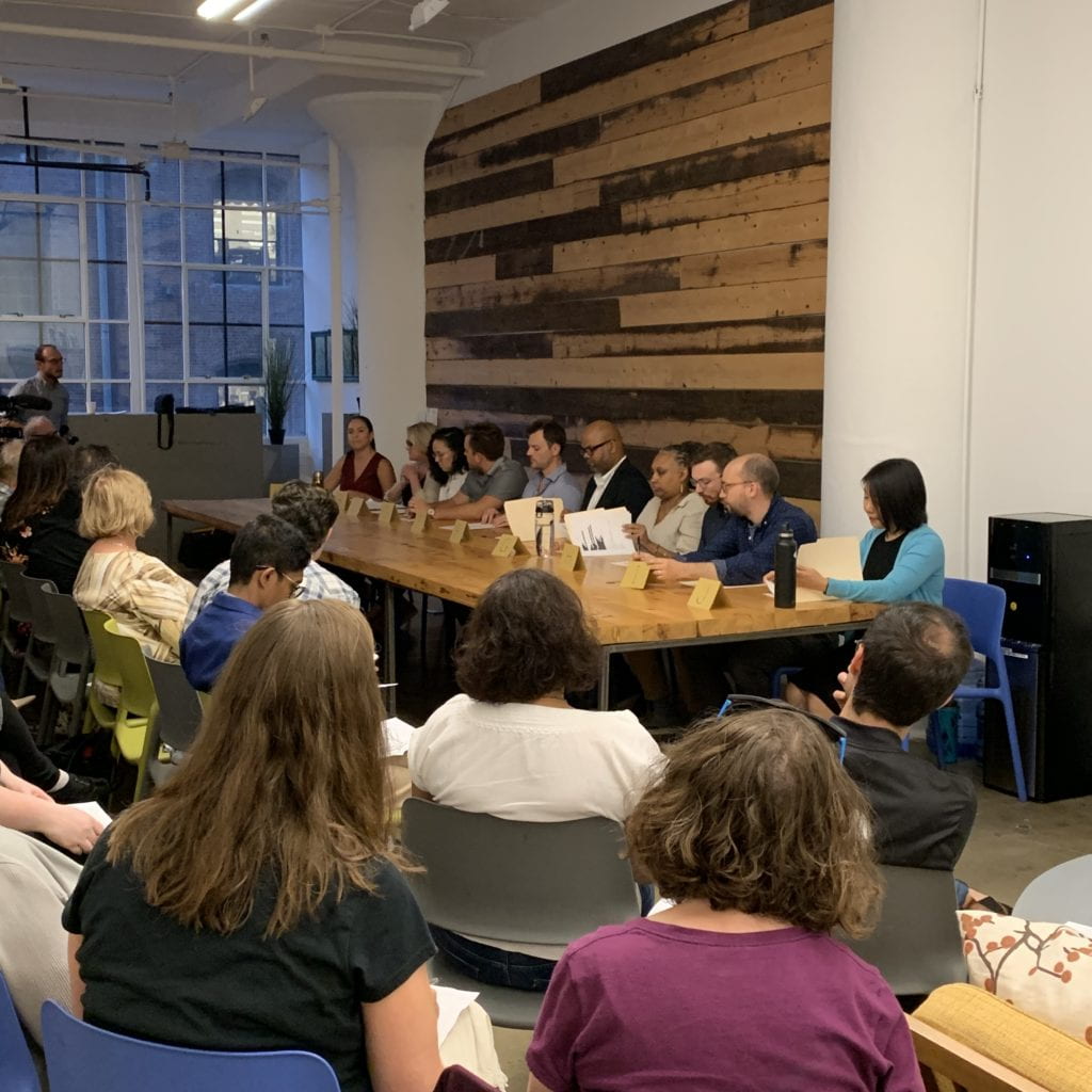 Actors seated at a table reading transcripts.