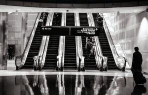 black and white photo of people on escalators in an airport