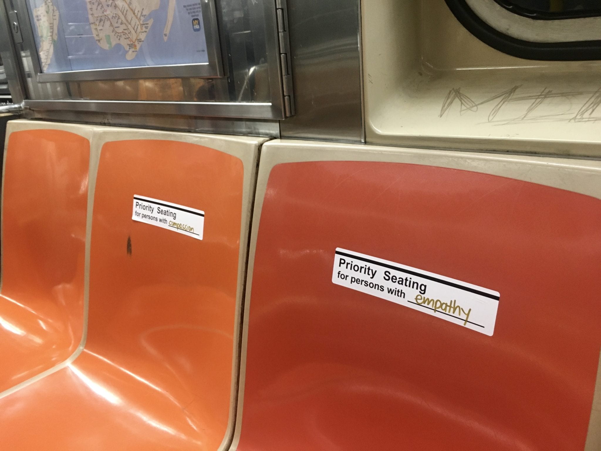 Priority seating stickers on two subway seats..