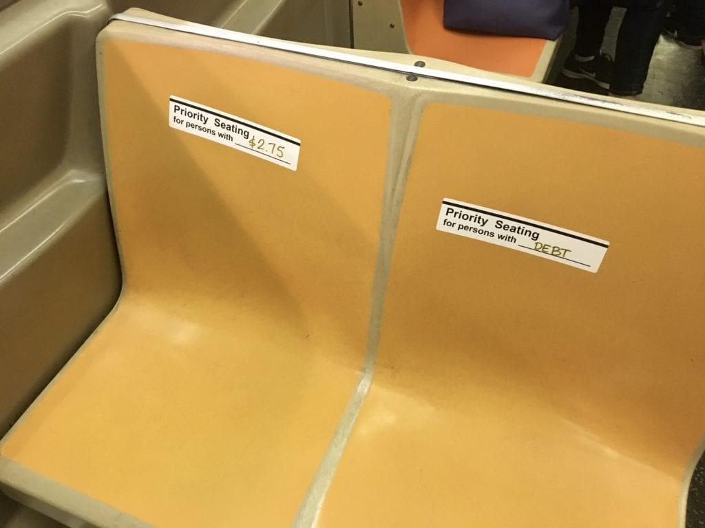 Priority seating stickers on two subway seats..