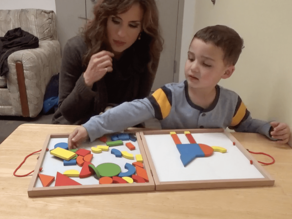 Mother and child are sitting together playing with geometrical blocks