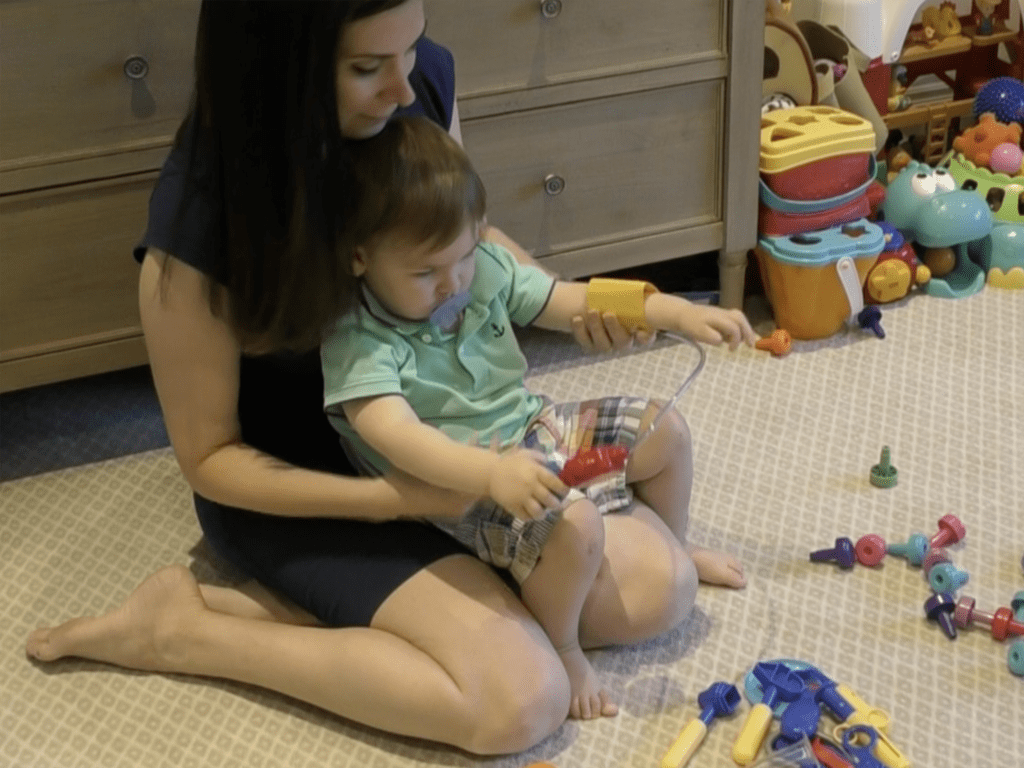 Mother and child are seated on the floor playing with blocks