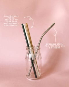 Compostable paper straws and one reusable metal straw in a glass