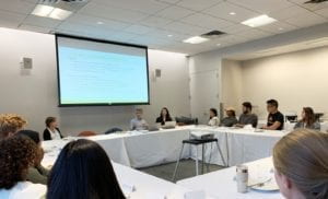 People sitting around a conference table discussing and viewing a screen presentation