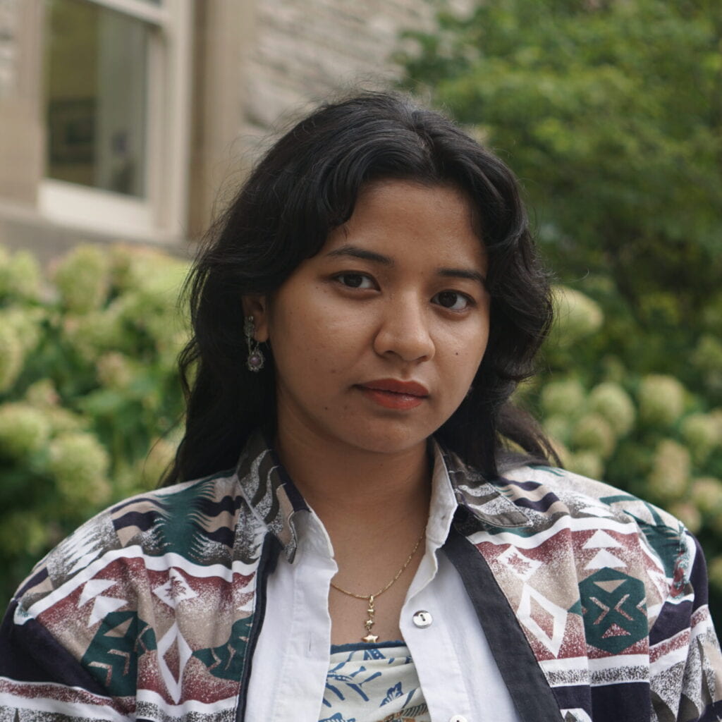 a woman with black hair looks at the camera