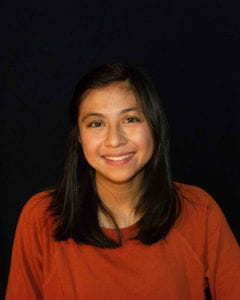 A woman with dark hair faces the camera and smiles.