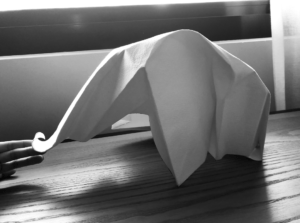 Single sheet of paper folded into an elephant shape. Paper is folded both with hard creases for the legs, and soft curves for the trunk and head. 