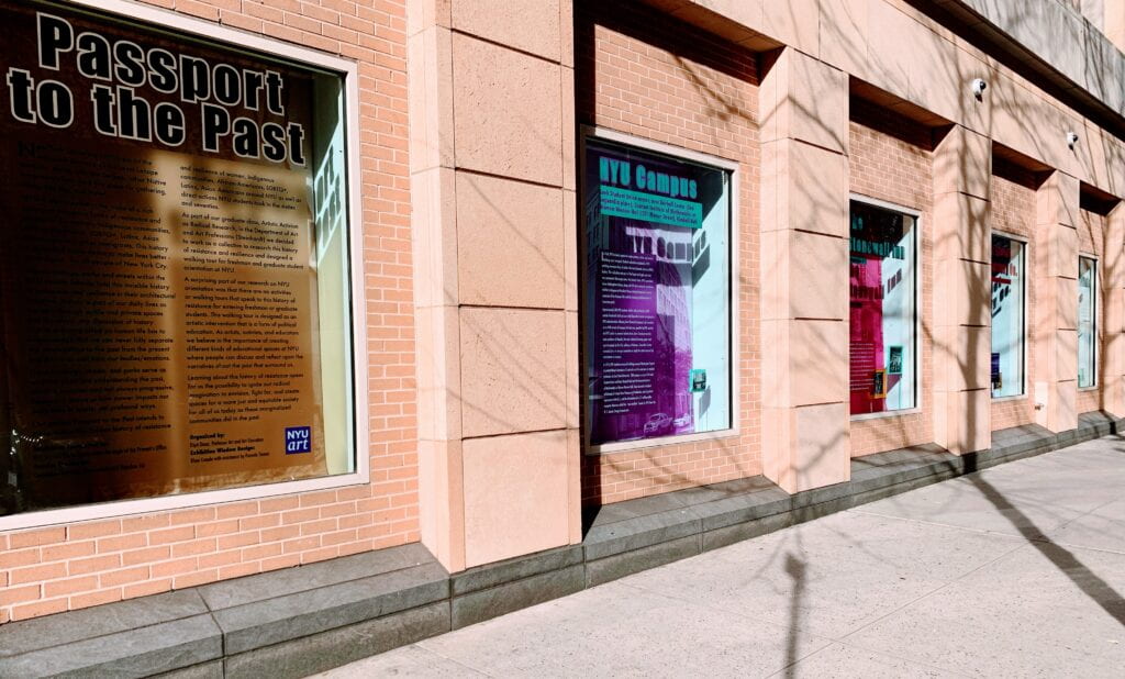 Image of a brick wall with glass cases depicting the project "Passport to the Past." Photo was taken outside and is well lit with some tree shadows