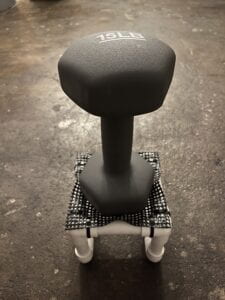 A 15 pound dumbbell sitting on top of a small PVC crib with a trampoline mesh top