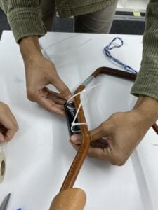 A group member shows how the zip tie tightens against the leather of the harness. 