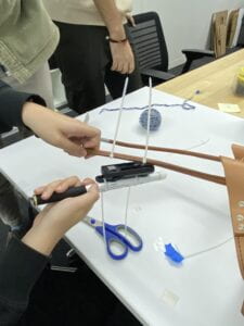 A group member pulls the cane off the Twist magnet attachment with their right hand while holding the harness steady over a table with their left.