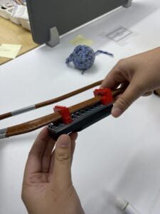 A group member holds up the harness leg with the Lego clamp attachment of the Fidlock Twist towards the camera.