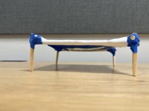 side profile of small rectangular cot held together with blue painter's tape