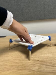 A hand pressing down on the white canvas of a small rectangular cot