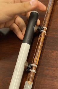 A pair of Snap magnets are attached to a retractable cane using epoxy. The cane is magnetically attached to magnets ziptied along the partially visible leg of a harness.