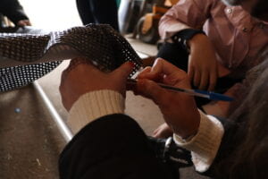 A young woman holding trampoline mesh up while marking a PVC pipe with a pen