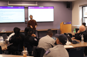 IMAGE DESCRIPTION: A classroom with seated NYU Department of Public Safety Officers listening to a man offering a lecture, part of Annual In-Service Training sessions to promote greater awareness of disability issues on campus.