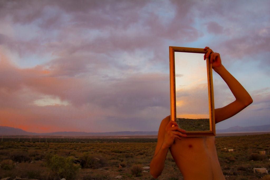 Figure with mirror in desert