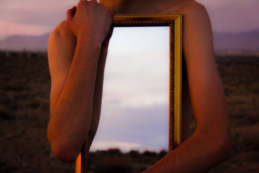 Figure with mirror in desert