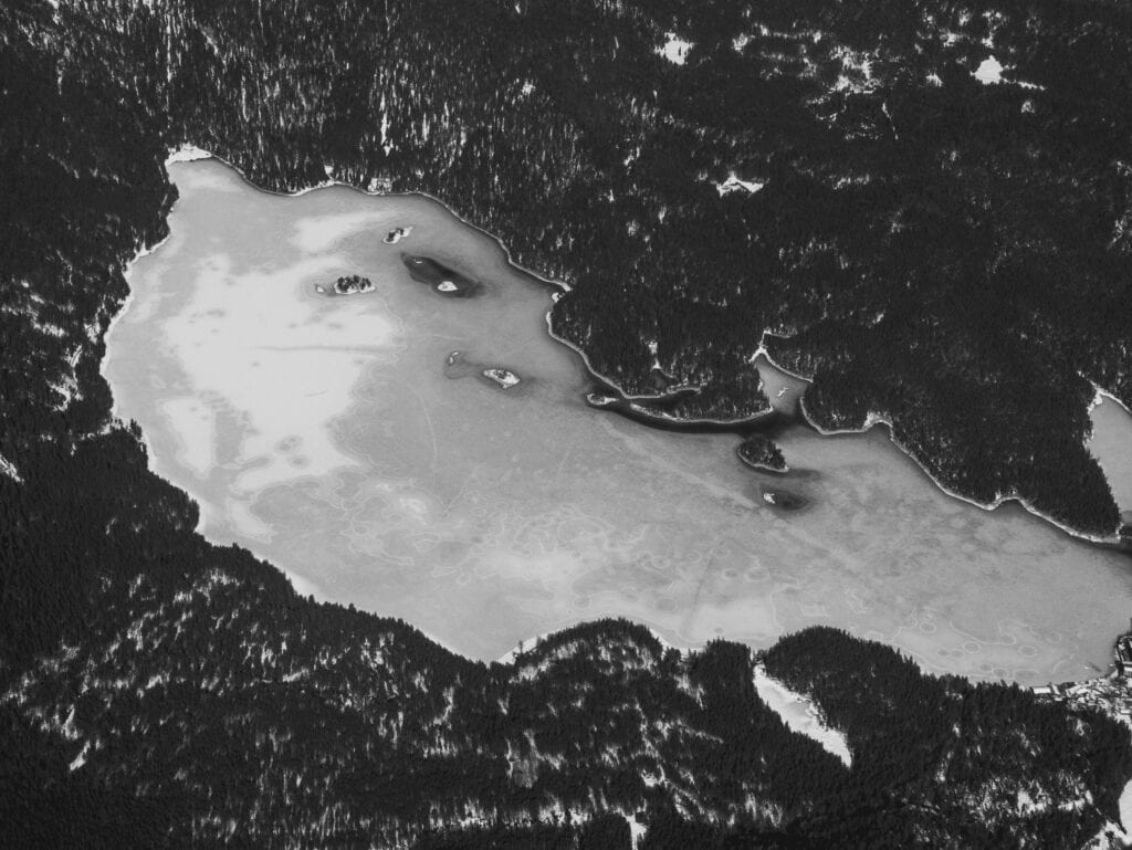 An aerial view of a frozen lake in the woods.