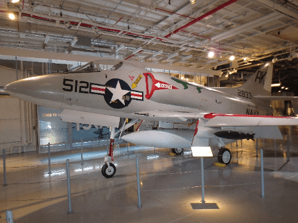 Side view of the grey jet plane, with markings “512” and a Navy star visible on the on the nose under the cockpit, and with “AK” and “2833” on the tail