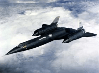  A black A-12 jet flies above clouds toward the lower left corner of the frame; its nose and body are narrow and sleek, with one large pointed jet engine on each side of the thin delta wing toward the back of the plane