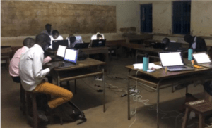 Students working on laptops at desks arranged in a circle