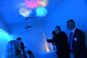 People stand in NYU Dentistry's Multisensory room lit with colorful lights.